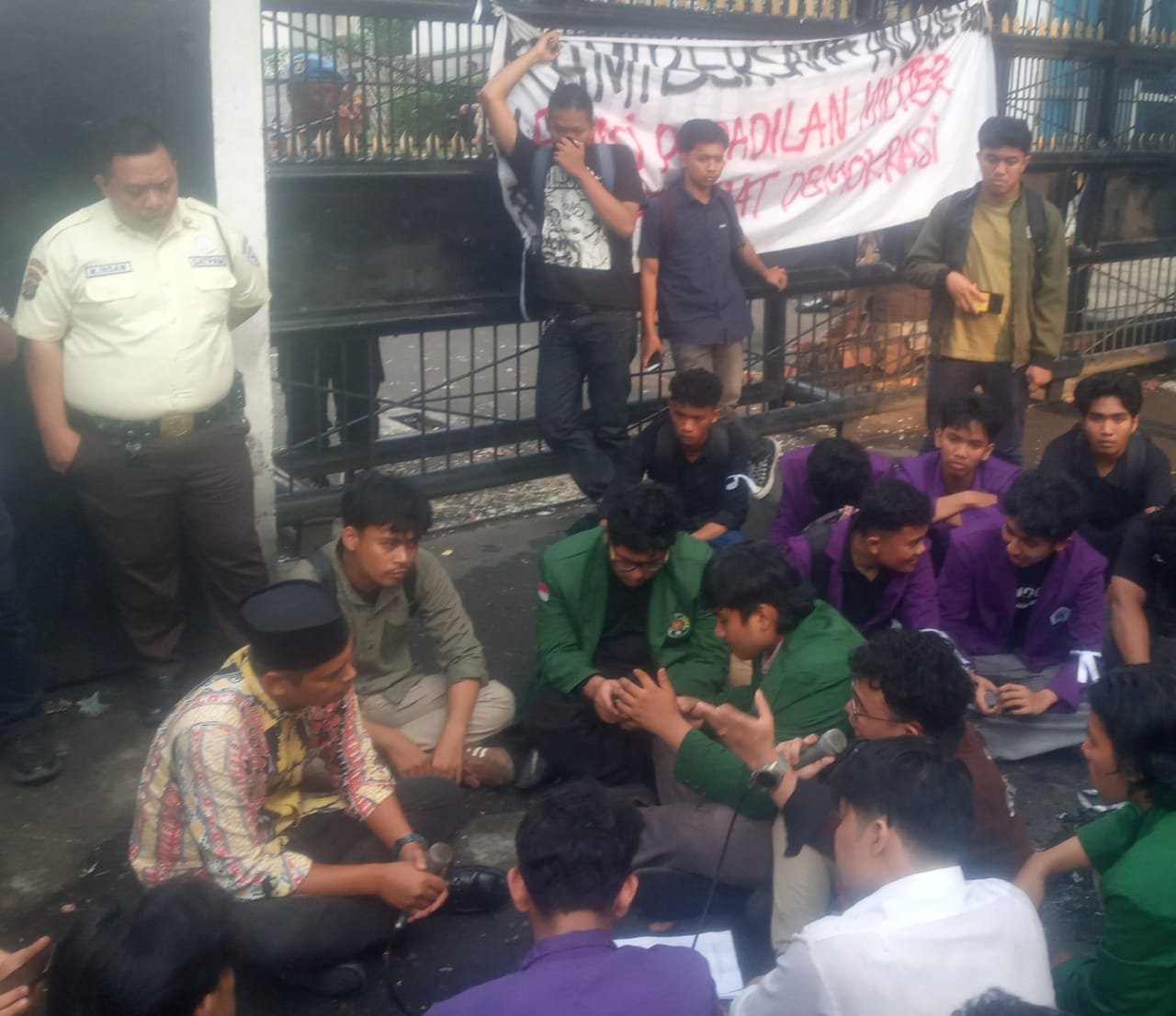 Anggota Komisi A, DPRD Sumut Gusmiyadi, SE (pakai peci) duduk di tanah di depan pintu gerbang masuk DPRD Sumut saat menerima aspirasi massa Aliansi BEM-SI Daerah Sumut. *