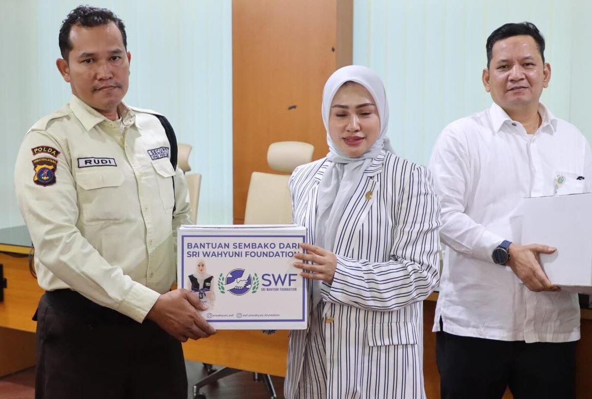 Ketua DPRD Sumatera Utara Sumut Erni Ariyanti, SH, MKn di di dampingi Sekwan DPRD Sumut Ali Sipahutar, SSTP, MAP menyerahkan bantuan paket sembako dari Sri Wahyuni Foundation kepada Rudi, perwakilan Satpam DPRD Sumut. 